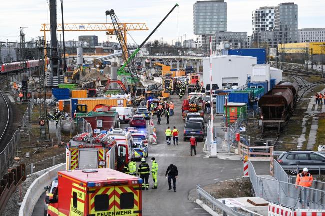 Firefighters, police officers and railway employees stand on a railway site in Munich, Germany (Sven Hoppe/dpa via AP)